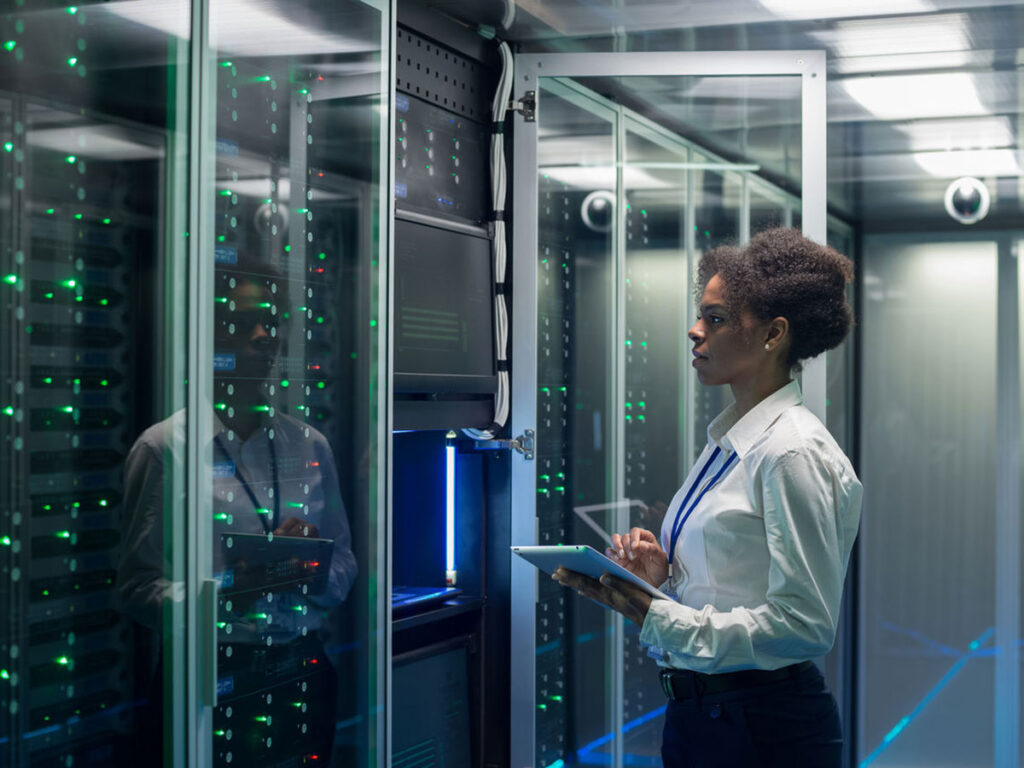 Technician working on a tablet in a data center full of rack servers running diagnostics and maintenance on the system